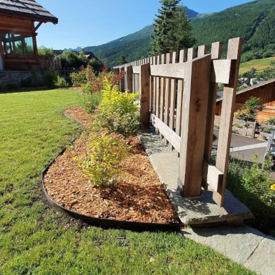 Massif de végétation et barrière en bois réalisés par Concept Jardin, spécialiste du jardin de montagne et d'altitude