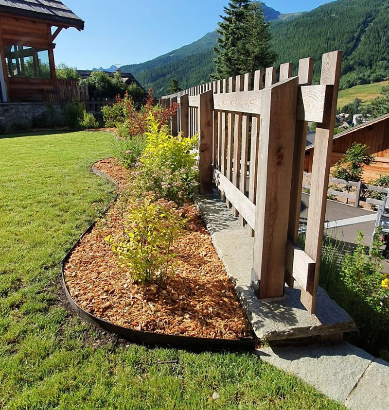 Barrière en bois derrière un massif d'arbustes fraichement plantés