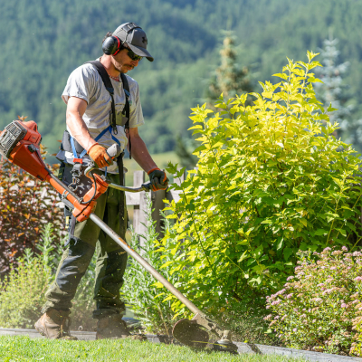 Entretien de vos espaces verts, un homme fignole une pelouse avec une débroussailleuse