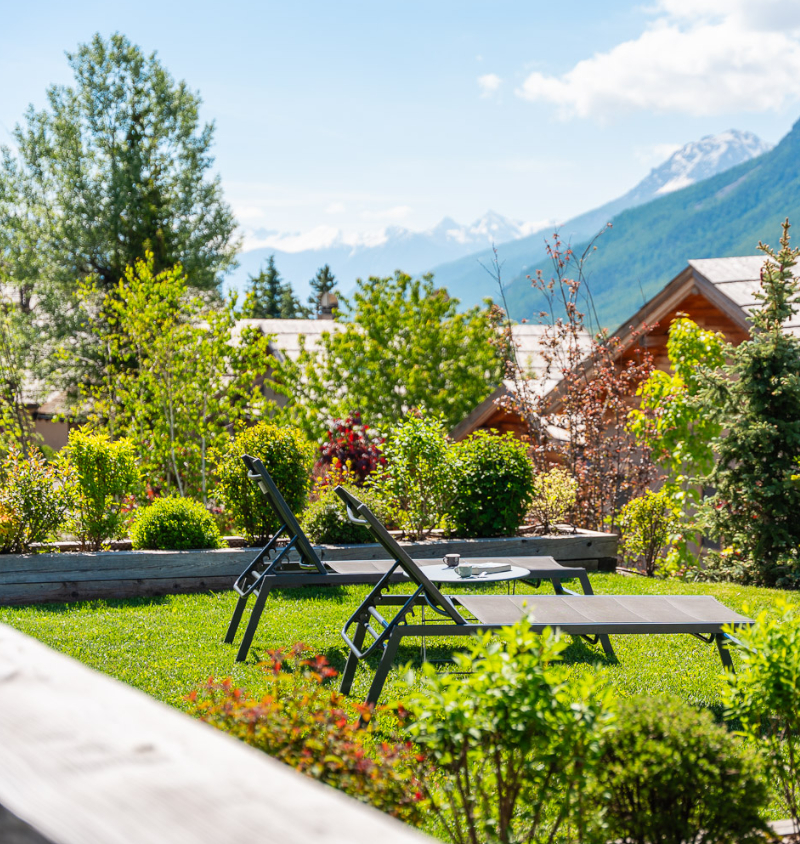 2 transats trônent sur une belle pelouse verte face à un paysage de montagnes